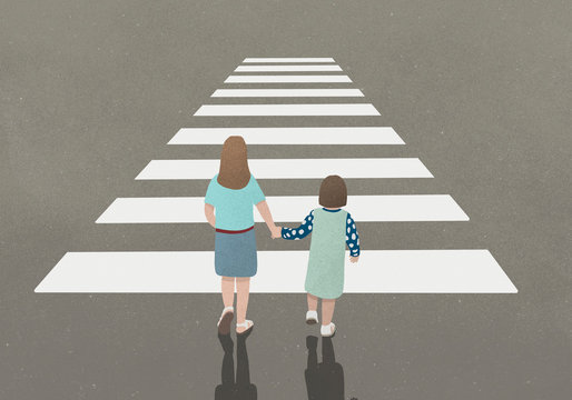 Woman and girl holding hands whilst walking through zebra crossing