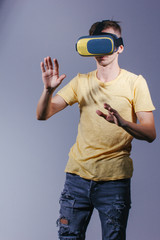 technology, gaming, entertainment and people concept - young man with virtual reality headset or 3d glasses. Studio shot, gray background.