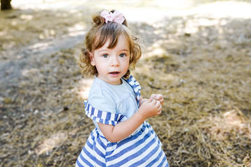 Sweet little girl outdoors with curly hair in the wind, walking in the park, copy space