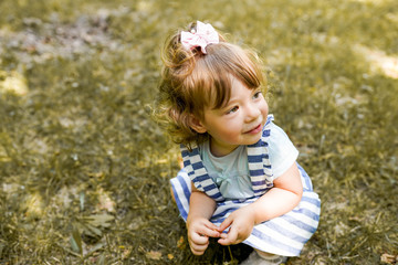 Cute little girl is playing with leaves in autumn park