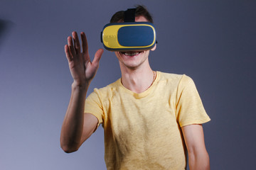 technology, gaming, entertainment and people concept - young man with virtual reality headset or 3d glasses. Studio shot, gray background.