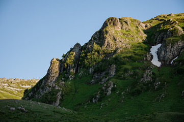 Beautiful view of the rocky hill with grass with the snow remnants