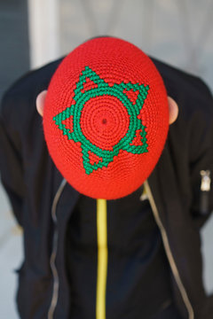 Boy with Moroccan star flag hat bowing, Marrakesh, Morocco