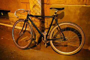 Fototapeta na wymiar a bicycle parked at a building by a drainpipe in the evening