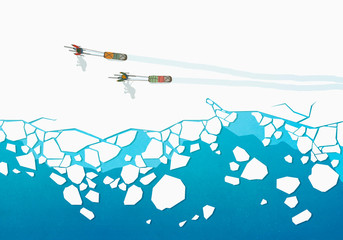 View from above people cross country skiing, pulling sleds over frozen ocean