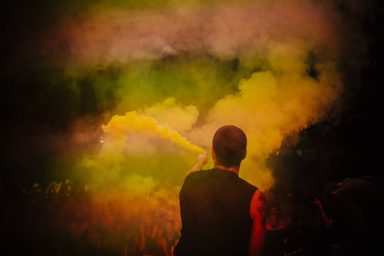 Male DJ on stage holding smoke bomb