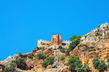 Fototapeta na wymiar Stone fortress on a rock against the sky. Stone fence on the mountain. Turkey, Alanya