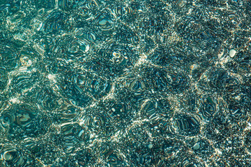 Sea pebbles under water. Textural seabed through clear, blue water.