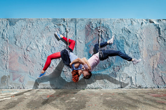 Modern aerialist dancers kissing, hanging upside-down