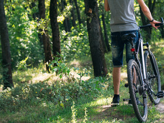 Fototapeta na wymiar Cyclist and mountain bike. Riding back roads through the forest. Back view