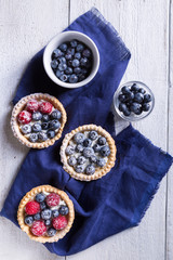 Cakes with fresh fruits on a white wooden background Top view