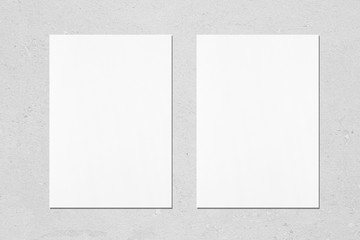 Two empty white vertical rectangle poster mockups with soft shadows on neutral light grey concrete wall background. Flat lay, top view - obrazy, fototapety, plakaty