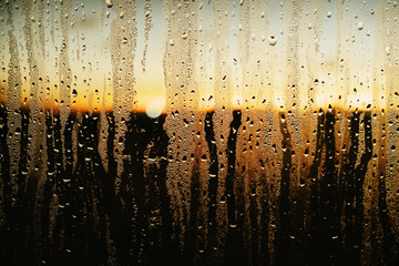 Raindrops and condensation on window with scenic sunset view