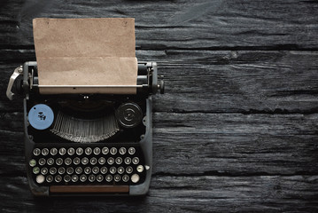 Old typewriter on a writer black wooden desk flat lay background with copy space.