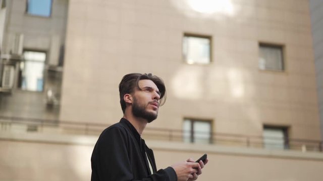 Young man with cell phone walking out of subway and looking around trying to navigate himself in unknown city, sow motion tracking shot