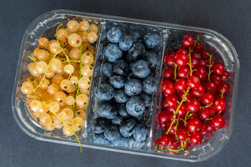 berries of red and white currants and blueberries in plastic packaging.