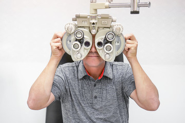 A man checks eyesight in a clinician oculist. Man checks his vision on the machine checking patient vision at eye clinic or optics store. Male patient to check vision in ophthalmological clinic