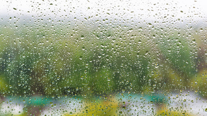 rain drops on home window and blurred city park