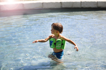 Fototapeta na wymiar Ein Junge planscht in einem Swimmingpool