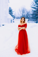 Fototapeta na wymiar Beautiful snow maiden girl with red hair on february nature. Snow fall in february. Long retro gown