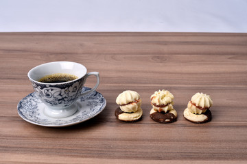 cup of coffee with cookie on table with background