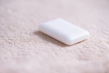 Fototapeta na wymiar White soap bar lying on a pale brown towel.