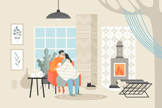 Young happy couple sitting in a chair and drinking tea. Man and woman enjoying evening near the fireplace in a cozy room