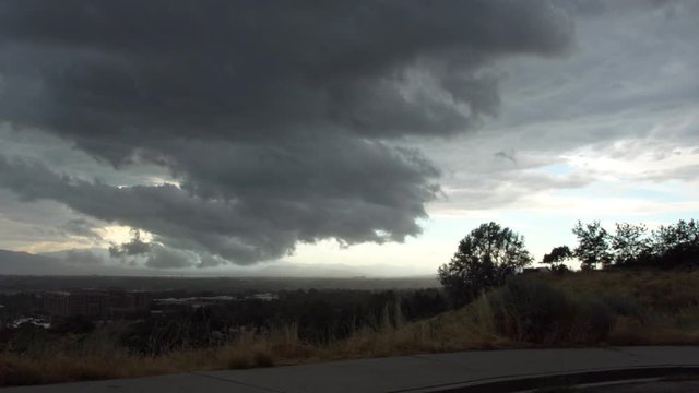 Wide view of dark clouds rolling in over city as storm blows into Utah Valley.