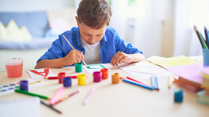 the child draws with a brush watercolor paints on paper the letter B