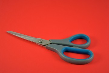 blue scissors isolated red background