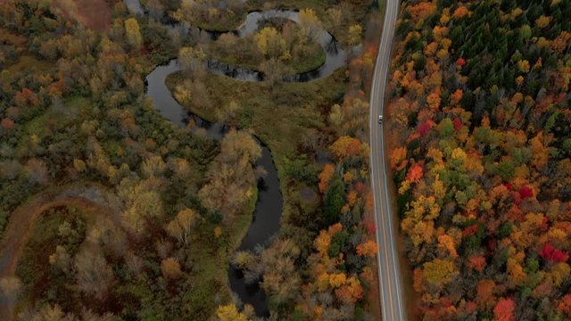 Aerial Pan Up: Car Driving On Road Through Brightly Colored, Forest Covered Plain - Dixville Notch, New Hampshire