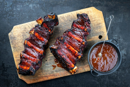 Barbecue chuck beef ribs with hot marinade and chili sauce as top on a wooden board with copy space