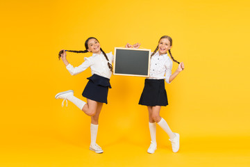 Obraz premium School announcement concept. Classmates initiative team yellow background. Join school club. Pupils community. School schedule. Informing changes. School girls cute pupils hold blackboard copy space