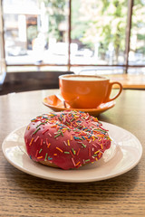 Cappuccino coffee with heart latte art and pink donut