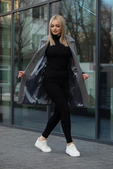 Young stylish hipster girl wearing modern trench coat walking in urban city smiling happy. 