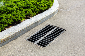 drainage grate on the edge of the curve of the asphalt road.