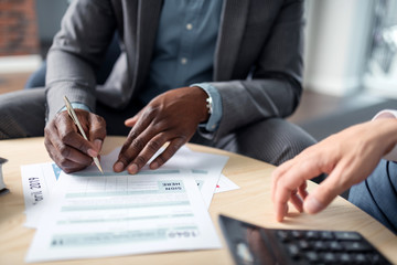 Man holding pen signing documents sitting near partner