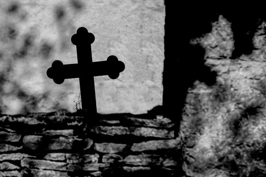 Cross over the masonry. Black and white gloomy photo.