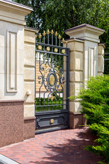 iron wrought iron gates entrance to the territory of the mansion with a capital stone fence and a...