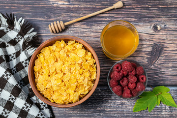 Creative flat lay overhead composition with organic gluten free corn flakes, ripe red raspberries,...