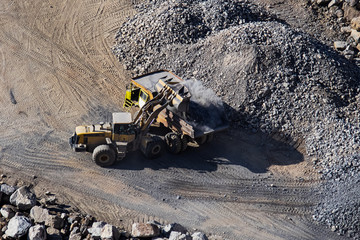 Excavator loading dumper truck on mining site stock photo