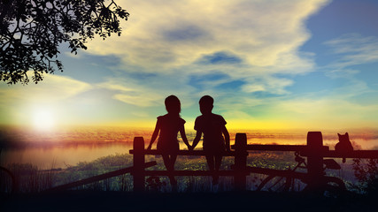 Boy and girl hold hands against the backdrop of summer sunset on the river