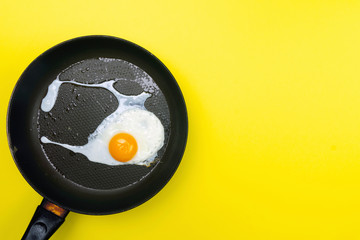 Fried eggs minimal concept on a bright yellow background. Egg yolk on a pan