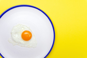 Fried eggs minimal concept on a bright yellow background. Egg yolk on a pan