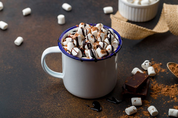 hot chocolate in an iron mug with marshmallow on dark rustic background