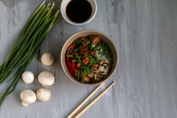 Traditional asian dish with rise and wok roasted meat, vegetables and mushrooms. Top view with space for text