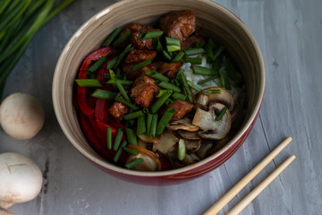 Traditional asian dish with rise and wok roasted meat, vegetables and mushrooms. Top view with space for text