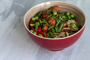Traditional asian dish with rise and wok roasted meat, vegetables and mushrooms. Top view with space for text
