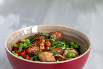 Traditional asian dish with rise and wok roasted meat, vegetables and mushrooms. Top view with space for text