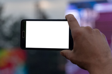 Smartphone in a man's hand. Video and photography on a mobile phone. White screen as a template, mock-up. Blank for embedding any image. Close-up.